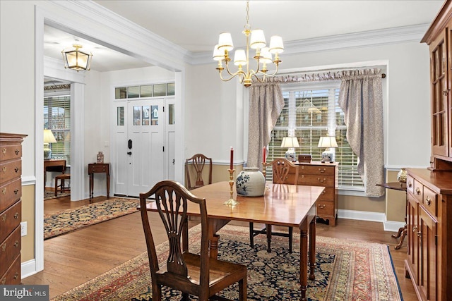 dining area with crown molding, a notable chandelier, and hardwood / wood-style flooring