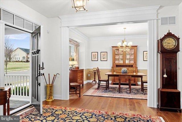 dining area with an inviting chandelier, crown molding, and hardwood / wood-style floors