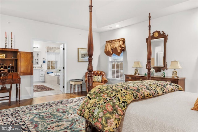 bedroom with hardwood / wood-style floors and ensuite bathroom