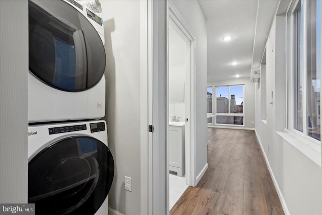 laundry room with light hardwood / wood-style flooring and stacked washer / dryer