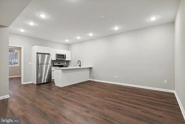 kitchen with dark wood-type flooring, white cabinets, decorative backsplash, appliances with stainless steel finishes, and kitchen peninsula