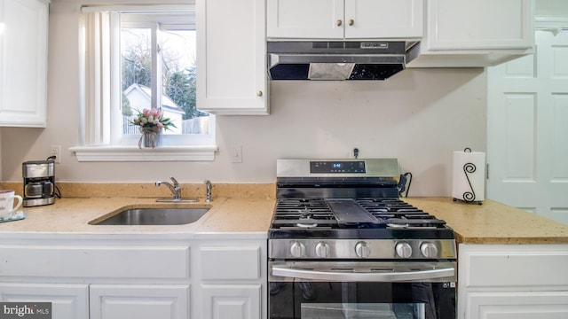 kitchen featuring sink, white cabinetry, light stone counters, and gas range