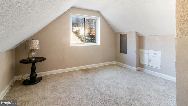 bonus room with a textured ceiling, light colored carpet, lofted ceiling, and electric panel