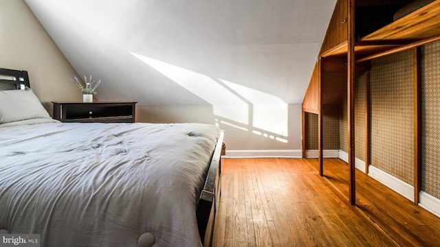 bedroom with lofted ceiling and wood-type flooring