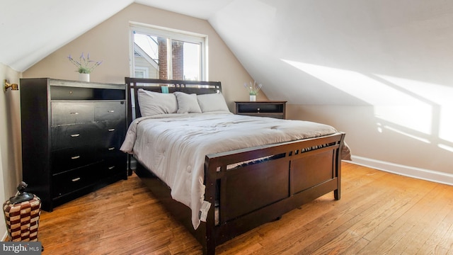 bedroom featuring light wood-type flooring and vaulted ceiling