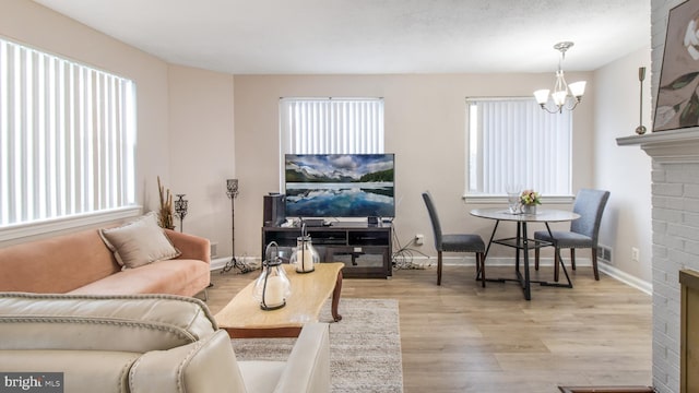 living room featuring a fireplace, an inviting chandelier, and light hardwood / wood-style flooring