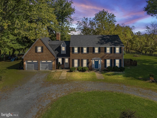 colonial home featuring a garage and a lawn