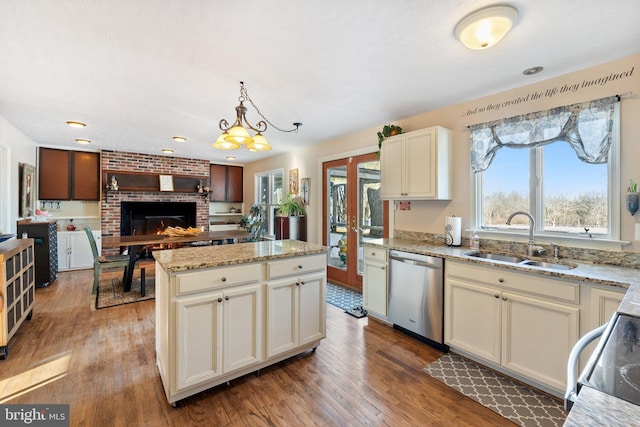 kitchen with pendant lighting, dishwasher, a center island, sink, and stove