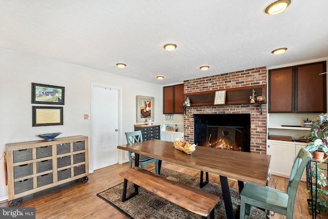 dining room featuring a brick fireplace and light hardwood / wood-style floors