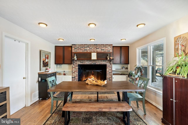 dining area with light wood-type flooring and a fireplace