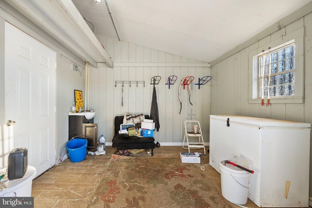 misc room featuring lofted ceiling and wooden walls