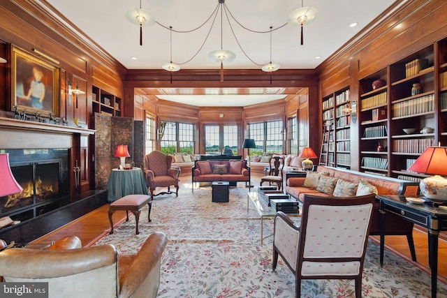 living room featuring built in shelves, ornamental molding, a high end fireplace, and wood-type flooring