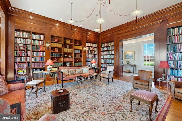 living area featuring hardwood / wood-style floors, crown molding, wooden walls, and built in features