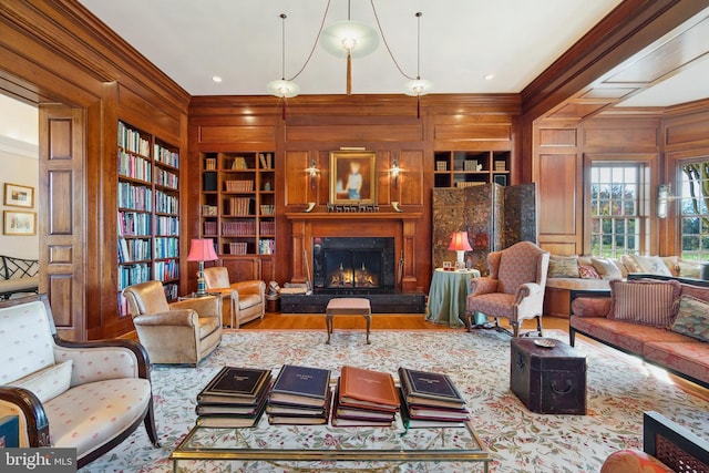 living room featuring ornamental molding, a fireplace, built in features, and wood walls