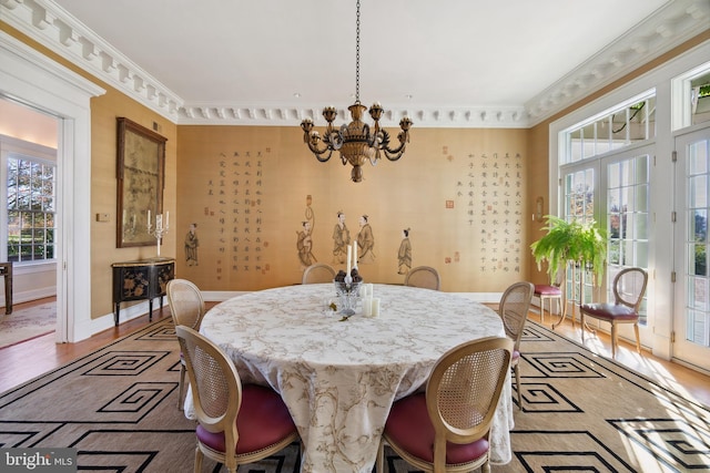 dining area featuring an inviting chandelier, crown molding, light hardwood / wood-style flooring, and french doors