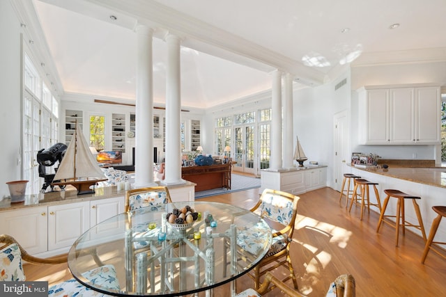 dining area with ornamental molding, light hardwood / wood-style floors, and ornate columns