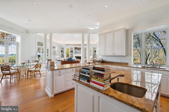 kitchen featuring light stone countertops, a kitchen island, sink, and white cabinets