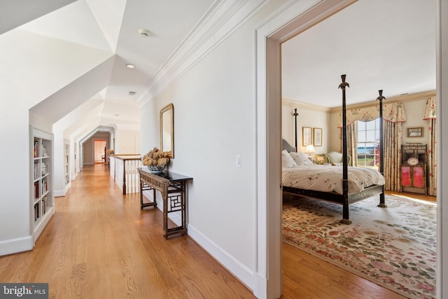 corridor featuring crown molding, built in features, and light wood-type flooring