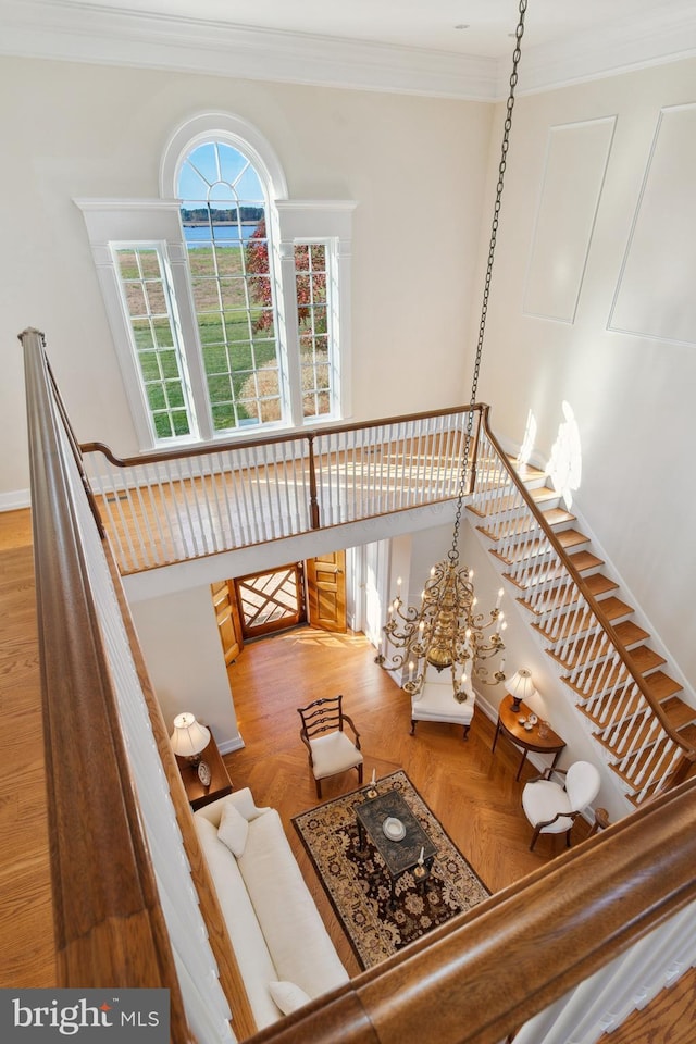 unfurnished living room with ornamental molding, parquet floors, and an inviting chandelier