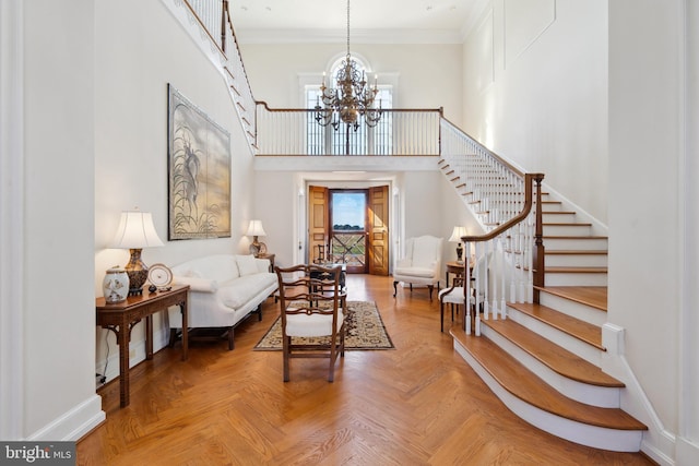 foyer with an inviting chandelier, parquet floors, ornamental molding, and a high ceiling