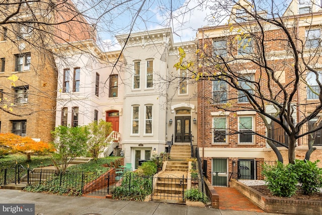 multi unit property featuring a fenced front yard, french doors, and brick siding