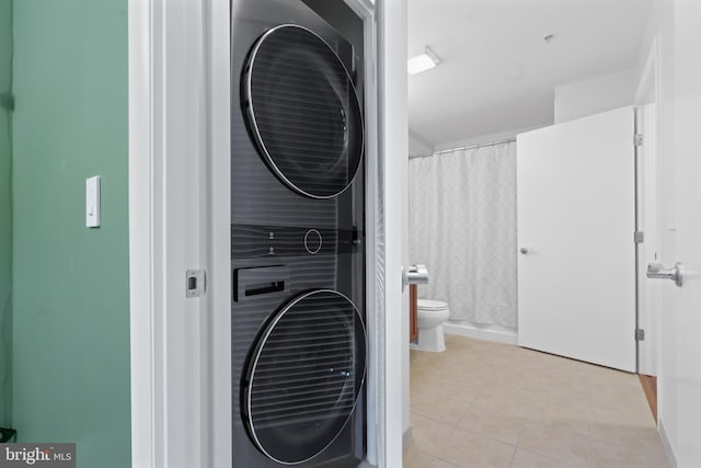 clothes washing area featuring light tile patterned floors and stacked washer / drying machine