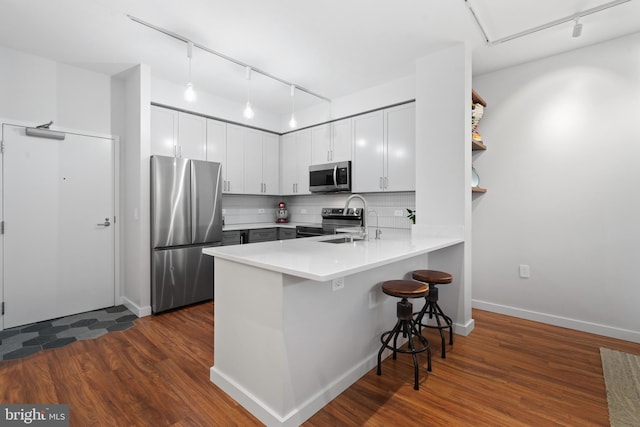 kitchen featuring decorative backsplash, a breakfast bar, white cabinets, and appliances with stainless steel finishes