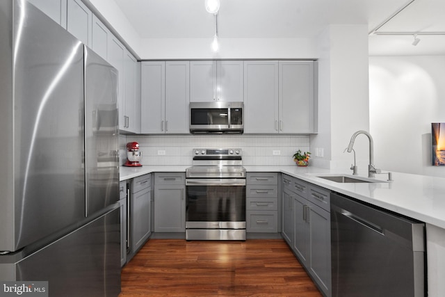 kitchen featuring decorative backsplash, appliances with stainless steel finishes, dark wood-type flooring, sink, and gray cabinets