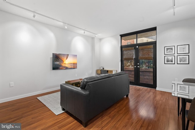 living room featuring rail lighting, dark wood-type flooring, and french doors