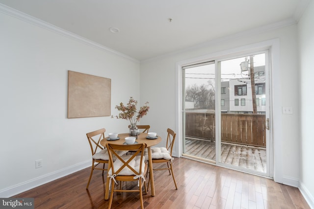 dining space with ornamental molding, wood finished floors, and baseboards