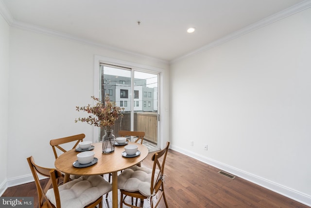 dining area with baseboards, visible vents, dark wood-type flooring, and ornamental molding