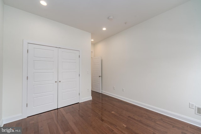 unfurnished bedroom with a closet, baseboards, dark wood-style flooring, and recessed lighting