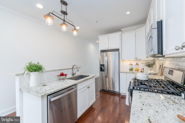 kitchen with pendant lighting, appliances with stainless steel finishes, a sink, and white cabinets