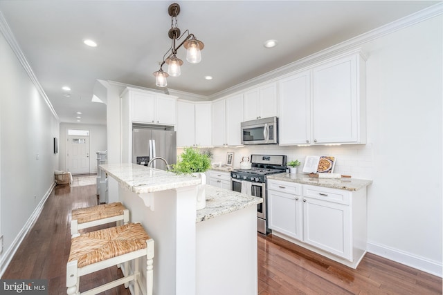 kitchen featuring a breakfast bar, a kitchen island with sink, white cabinetry, and stainless steel appliances