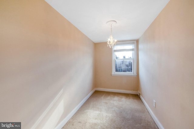 carpeted spare room with a notable chandelier