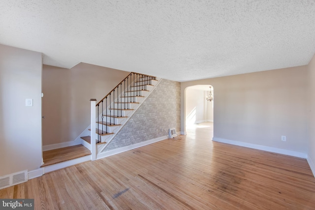 unfurnished living room with a textured ceiling and light hardwood / wood-style flooring