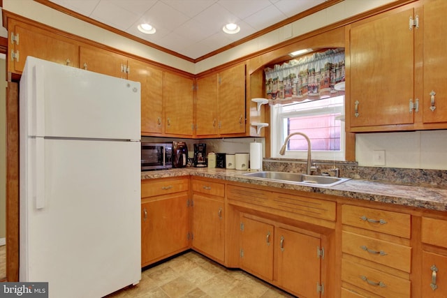 kitchen with crown molding, sink, and white refrigerator