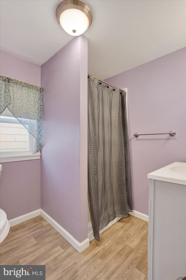 bathroom featuring a shower with curtain, vanity, wood-type flooring, and toilet