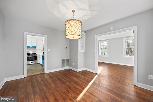 unfurnished dining area with dark wood-type flooring, visible vents, and baseboards