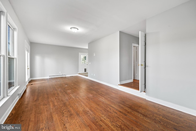 unfurnished living room featuring a baseboard radiator, baseboards, baseboard heating, and wood finished floors