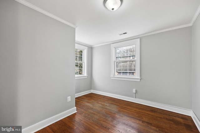 spare room with baseboards, visible vents, dark wood-style flooring, and crown molding