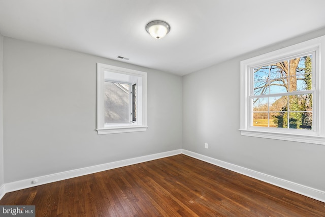 unfurnished room with visible vents, baseboards, and dark wood-type flooring