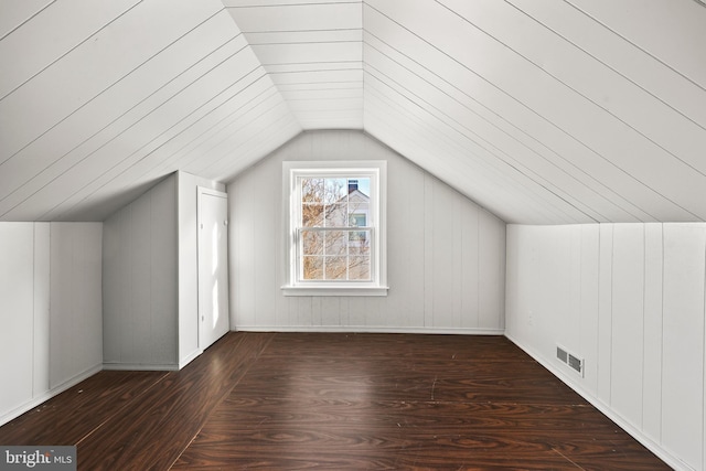 additional living space with dark wood finished floors, visible vents, and vaulted ceiling