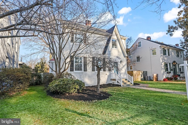 view of side of property featuring a chimney, fence, central AC, and a yard