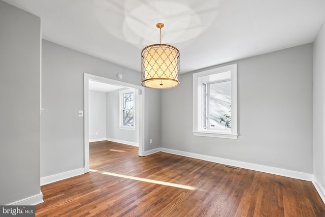 unfurnished dining area featuring baseboards and dark wood finished floors