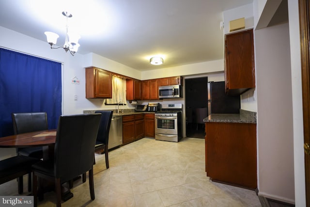 kitchen featuring hanging light fixtures, dark stone countertops, stainless steel appliances, and an inviting chandelier