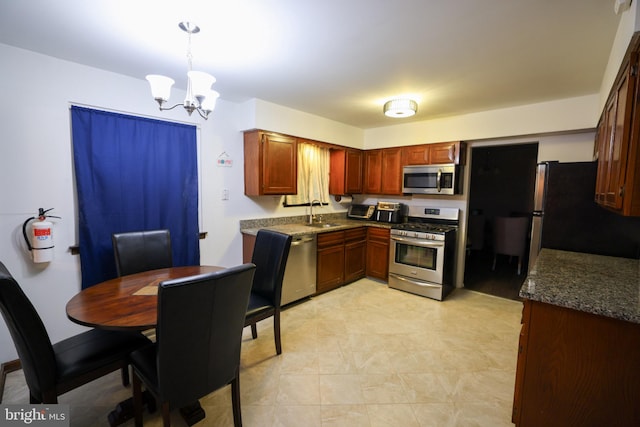 kitchen featuring a notable chandelier, appliances with stainless steel finishes, sink, decorative light fixtures, and dark stone counters