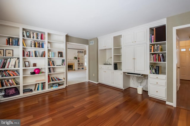 office space with built in desk and dark wood-type flooring