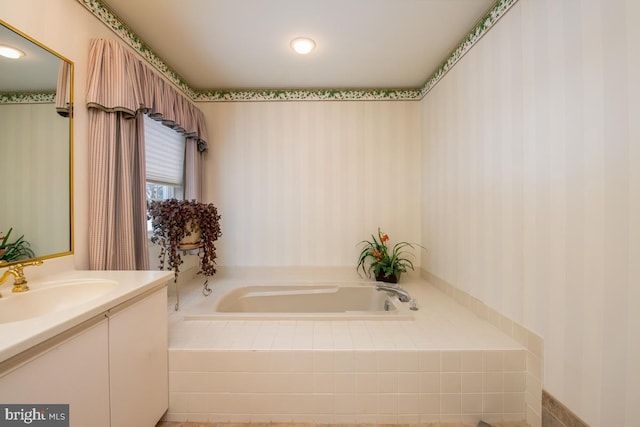 bathroom with tiled bath and vanity