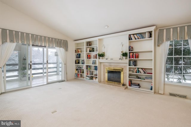 living area with carpet flooring, a high end fireplace, and vaulted ceiling